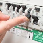 safety switch a finger about to flick on a circuit breaker beside a safety switch