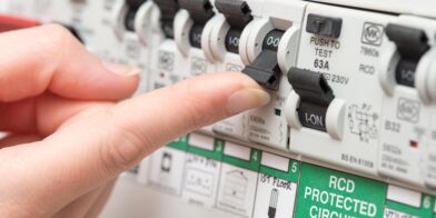 a finger about to flick on a circuit breaker beside a safety switch